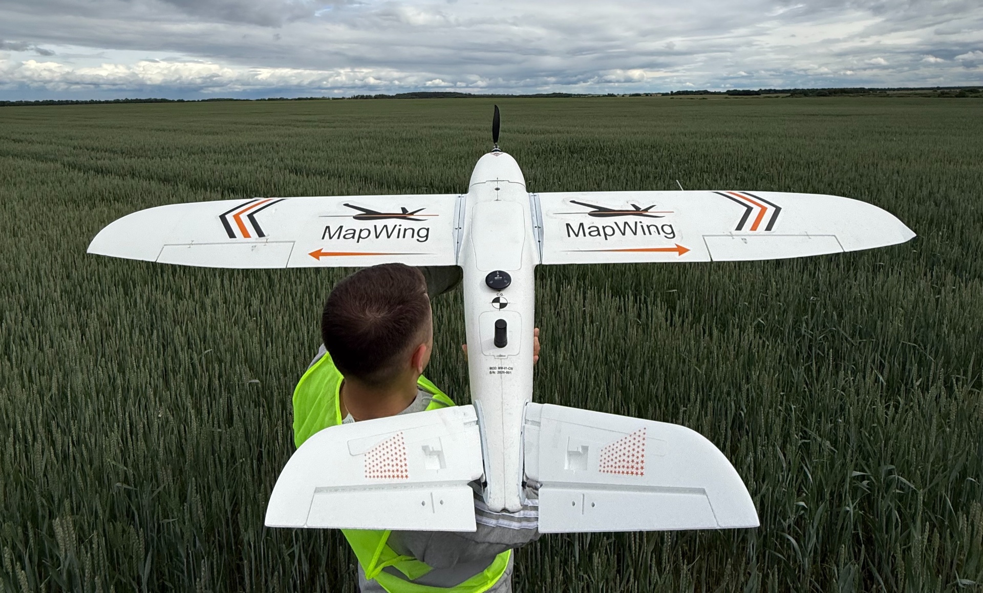 MapWing operator preparing the fixed-wing UAV in a wheat field